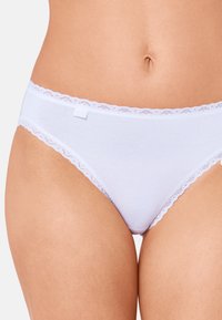 Valkoiset puuvillabriiffit, joissa on herkkä pitsireunus vyötärön ympärillä. Sileä pinta, minimalistinen muotoilu ja etiketti sijoitettu taakse.