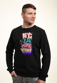 Sudadera negra con texto de estilo graffiti en colores: "NYC," "LA," "París," y "Londres" con goteos en púrpura. Material de algodón, diseño de cuello redondo.