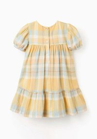 Abito giallo a quadri con maniche a palloncino corte, chiusura con bottoni sul retro e orlo a volant a strati. Realizzato in tessuto leggero e morbido.