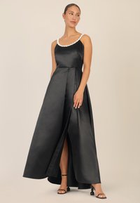 Schwarzes Satin-Kleid mit tailliertem Oberteil, perlenverziertem Ausschnitt und bodenlangem Rock mit einem Seitenschlitz. Schlichte Träger und elegantes Design.