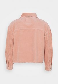 Różowa kurtka z sztruksu z kołnierzem, długimi rękawami i krótkim krojem. Charakteryzuje się pionowym prążkowaniem i mankietami zapinanymi na guziki.