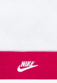 Κάλτσες Nike με λευκό επάνω μέρος και φωτεινό ροζ πλεκτό τελείωμα με λευκ�ή κεντημένη λεπτομέρεια λογότυπου. Το υλικό φαίνεται μαλακό και ελαστικό.