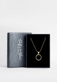 Gul cirkelhänge på ett delikat kedja, visad i en smyckeslåda med svart sammet och en texturerad silverexteriör.