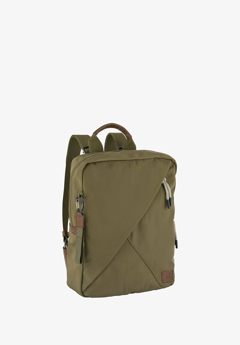 Mochila compacta de color verde oliva con diseño frontal diagonal, correas acolchadas, asa superior y tiradores de cremallera con cordón blanco sobre un fondo blanco.