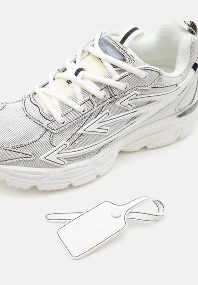 Άσπρα και μαύρα sneakers Off-White με σχέδιο βέλους, λευκά κορδόνια και μια ταυτότητα που ταιριάζει με ορατά ράμματα σε λευκό φόντο.