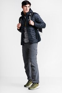 Czarna puchowa kurtka, szary polarowy bluza z kapturem, szare spodnie cargo i oliwkowe buty sportowe. Zawiera plecak z białym akcentem.