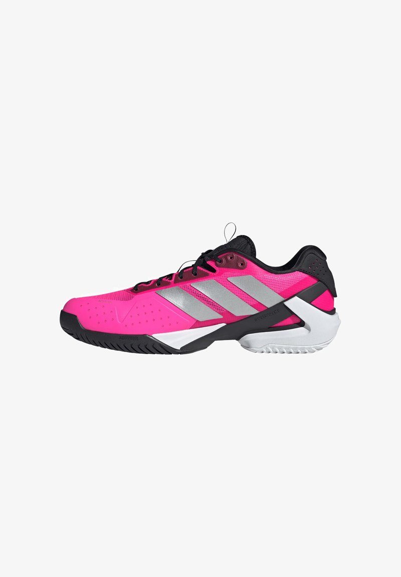 Shoe atlético em rosa brilhante e preto com riscas prateadas, atacadores pretos e uma sola texturizada em preto e branco, vista de lado.