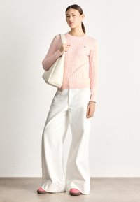 Ružový sveter s vrkočovým vzorom, krémová kabelka, široké biele nohavice a ružové topánky, so zvýraznenou textúrou látky a ležérnym, uvoľneným strihom.
