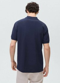 Tummansininen polo-paita, jossa on rento istuvuus, lyhyet hihat ja klassinen kaulus. Valmistettu puuvillasta ja sillä on sileä rakenne.