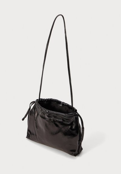 Borsa a spalla nera e lucida con apertura arricciata e lungo manico sottile, su uno sfondo bianco uniforme.