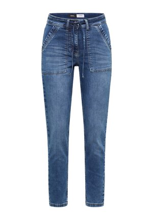 Niebieskie, dopasowane spodnie jeansowe z wiązanym paskiem w talii oraz dużymi kieszeniami naszywanymi z przodu, oznaczone "Cecil Denim" na wewnętrznej taśmie w pasie.