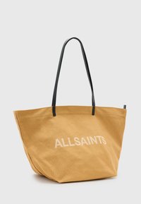 Canvas draagtas in mosterdgeel met zwarte leren hengsels. Voorzien van het "ALLSAINTS" logo in het wit, groot en ruim ontwerp.