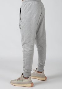 Grå sweatpants med sidelommer, elastisk talje og diskret logo-detalje. Stylet med lyse sneakers med struktureret overdel.