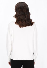 Maglione bianco con maniche lunghe, scollatura rotonda e orlo a coste. Tessuto morbido e vestibilità comoda. Design minimalista senza motivi o dettagli visibili.