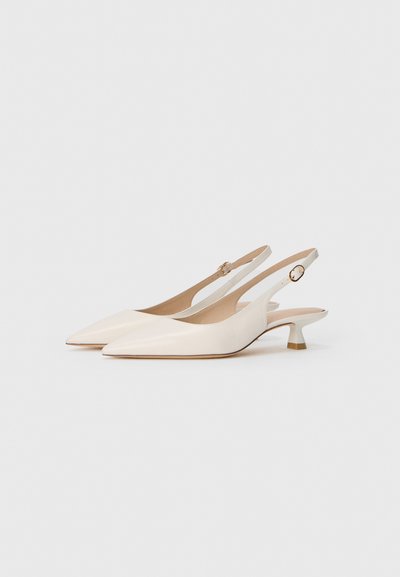 O pereche de pantofi slingback eleganți, de culoare albă murdară, cu vârf ascuțit și toc kitten mic, cu catarame aurii reglabile, pe un fundal alb.