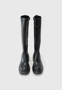 Pair of tall black leather boots with chunky soles and side zippers, standing upright on a plain light background.