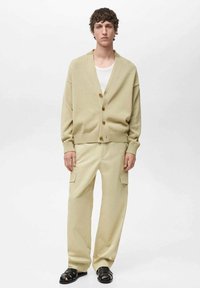 Beige cardigan med V-ringning, knäppning och ribbade manschetter, tillsammans med ljusbeiga cargobyxor med sidofickor och en avslappnad passform.