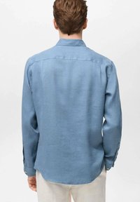 Light blue long-sleeve shirt made of a textured fabric, featuring a classic collar and buttoned cuffs, shown from the back.