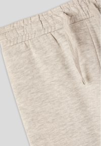 Jasnobeżowe spodnie dresowe z elastycznym pasem, sznurkiem do regulacji i miękką, szczotkowaną teksturą. Posiadają subtelny melanżowy wzór na całej powierzchni.