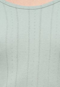 Ανοιχτό πράσινο ριμπ μπλουζάκι με οριζόντιες και κάθετες ρίγες, μικρά διαμάντια σε ολόκληρο το ύφασμα και στρογγυλή λαιμόκοψη.