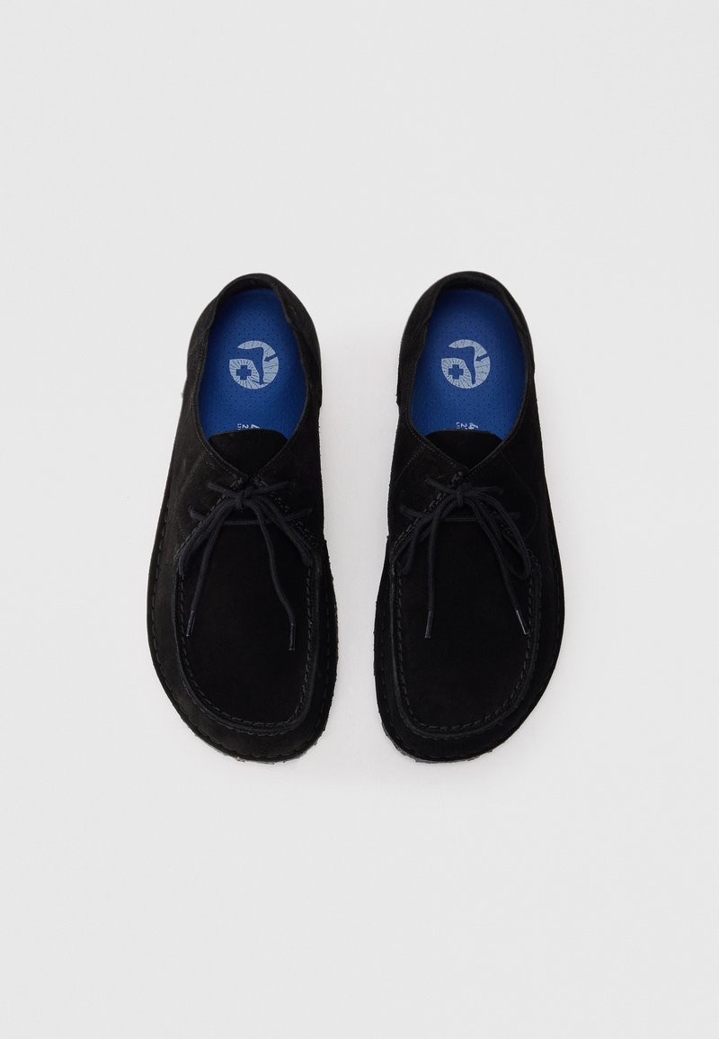 Zwarte suède veterschoenen in mokassinstijl met blauwe binnenzolen, met een wit cirkelvormig logo, zij aan zij geplaatst op een witte achtergrond.