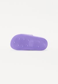 Lilla gummi såle med en teksturert overflate som har sirkulære og trekantede mønstre, designet for grep og stabilitet.