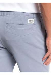 Světlé modré šortky vyrobené z lehkého materiálu, se zadní kapsou s štítkem. Hladká textura a rovný střih.