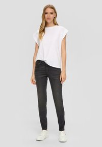 Witte T-shirt met korte mouwen en een relaxte pasvorm, gecombineerd met zwarte skinny jeans en witte sneakers. Eenvoudig ontwerp zonder patronen of accenten.