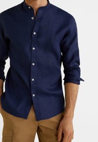 Donkerblauw overhemd met lange mouwen en een bandenhals, voorzien van witte knopen en opgerolde manchetten, gemaakt van lichtgewicht stof.