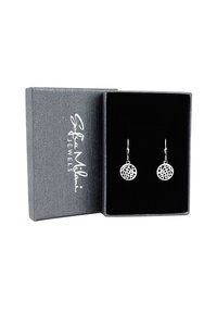 Silverörhängen med cirkulär, intrikat utskärningsdesign som visas i en grå, texturerad smyckesask med svart sammetfoder.