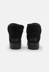 Botas de tobillo de ante negro con punta redonda, collar acolchado y suelas de goma. Presenta la marca "Gioseppo" en el talón.