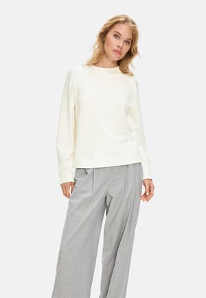 Cream-colored long-sleeve sweatshirt with a v-shaped neckline, paired with light gray plaid wide-leg trousers, showcasing a smooth fabric texture.