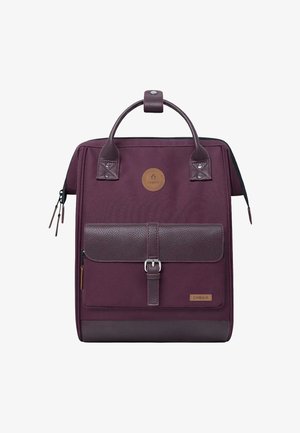 Sac à dos violet de forme carrée avec des poignées en cuir, une poche avant avec boucle, et deux fermetures éclair de chaque côté.