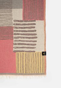 Textile blanket featuring geometric patterns in orange, yellow, gray, and beige, with fringe edges and a black label in the corner.