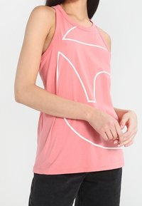 Top rosa realizzato in tessuto morbido, caratterizzato da un design astratto bianco. Senza maniche, con scollatura tonda, ha una vestibilità comoda.