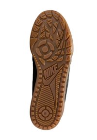 Suela de zapatilla Nike en negro y goma natural; presenta un patrón de textura para mayor agarre, con el logotipo destacado.