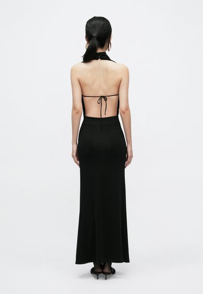 Μαύρο φόρεμα με halter σχέδιο, ανοιχτή πλάτη, μήκος μέχρι το πάτωμα, ομαλή υφή και λεπτές κορδέλες στον λαιμό και στη χαμηλή πλάτη.