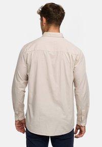 Hellbeiges langärmliges Hemd mit traditionellem Kragen, Knopfmanschetten und abgerundetem Saum, aus atmungsaktivem Stoff gefertigt. Rückansicht gezeigt.