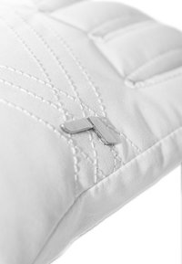 White quilted pillow with visible stitching patterns and a small silver metal clip detail on the surface. Soft texture.