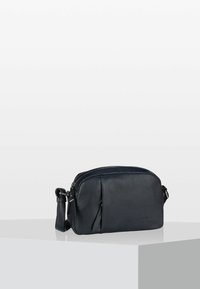 Piccola borsa crossbody in pelle nera con texture, dotata di un compartimento principale con zip e una tracolla regolabile, esposta su un piedistallo bianco.