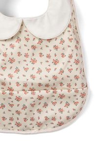 Beige dækkeserviette med hvid krave, prydet med et blomsterdesign i pink og grøn. Glat tekstur med en lomme foran.