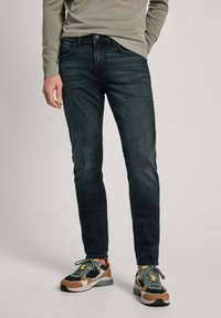 Mörka denimjeans med en figurnära design, lätt stretch och synliga söm detaljer. Bärs med flerfärgade sneakers och en lätt tröja.