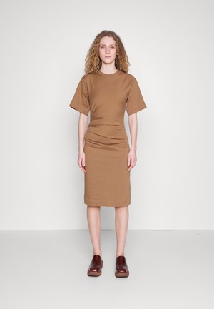 Καφέ βαμβακερό φόρεμα T-shirt με κοντά μανίκια, εφαρμοστή μέση και ίσιο φουστάνι. Συνδυάζεται με σκούρα καφέ παντόφλες. Υφασμάτινη υφή.