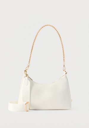 Bolso rectangular blanco con asa superior de cadena dorada y correa de hombro de tela blanca desmontable sobre un fondo blanco.