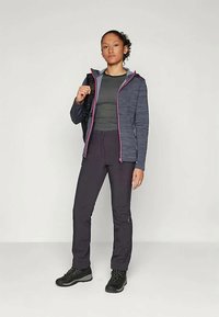 Conjunto de roupa exterior com uma jaqueta azul marinho com detalhes em rosa, uma blusa cinza, calças escuras e botas de caminhada pretas. Tecido texturizado em toda a peça.