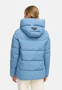 Ljusblå puffjacka med huva, har kviltade sektioner och en logotyp på baksidan. Slätt material och avslappnad passform.