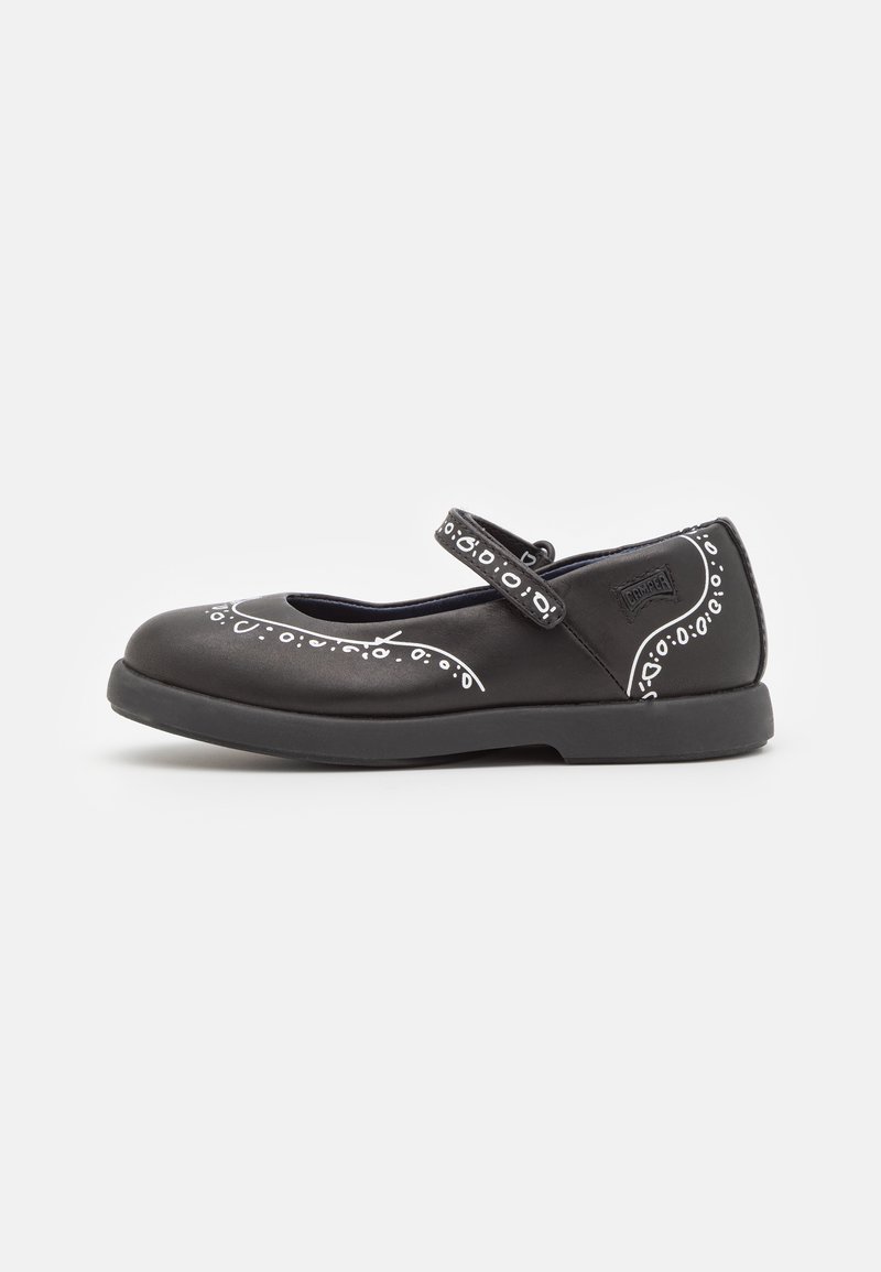 Zapato negro estilo Mary Jane con punta redonda, adornado con patrones decorativos blancos y una sola correa ajustable en el empeine.