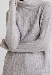 Maglione grigio a collo alto con maniche lunghe, realizzato in morbido tessuto a maglia, con una vestibilità comoda e un delicato dettaglio di texture.