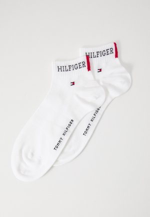 White cotton socks with red and navy accents. "HILFIGER" logo embroidered on the cuff and "TOMMY HILFIGER" printed on the side.
