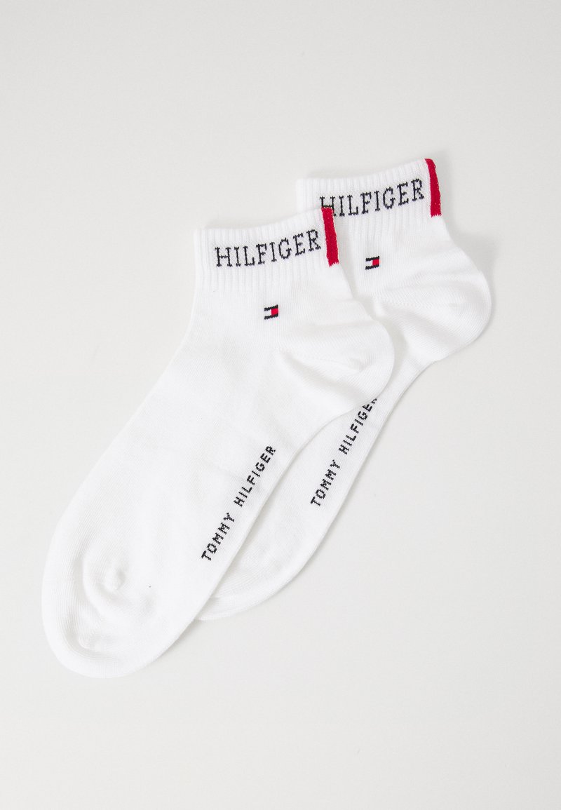 Hvite bomullssokker med røde og marineblå detaljer. "HILFIGER" logo brodert på kanten og "TOMMY HILFIGER" trykt på siden.